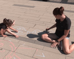 Děti malovaly křídami na chodníku před knihovnou 